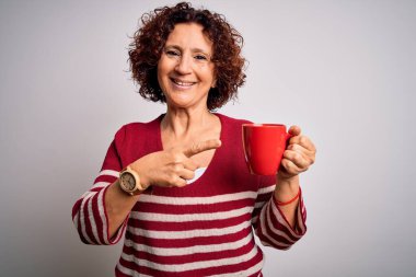 Orta yaşlı kıvırcık saçlı kadın izole edilmiş beyaz arka planda bir kupa kahve içiyor.