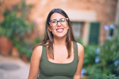 Mutlu ve kendinden emin gülümseyen genç ve güzel bir kadın. Kasaba caddesinde yüzünde gülümsemeyle dikilirken