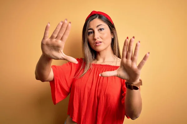 Young beautiful woman colorful summer style over yellow isolated background doing frame using hands palms and fingers, camera perspective