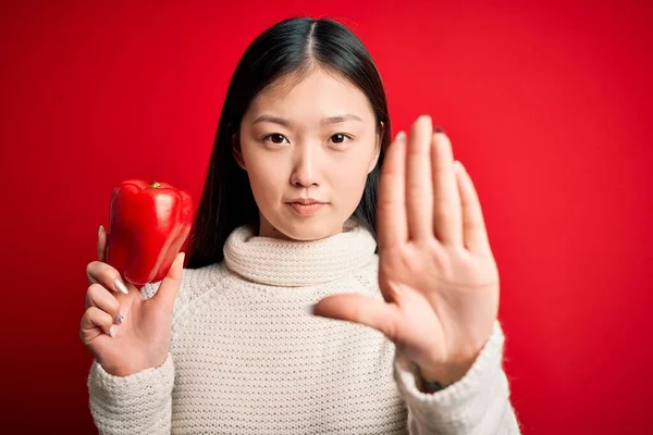 年轻的亚洲女人 带着健康而新鲜的红辣椒 带着严肃而自信的表情和防守姿态 张开双手 做着停止的手势 — 图库照片