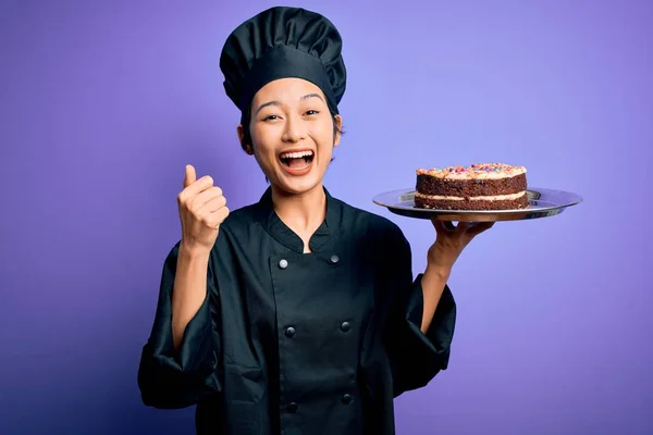 身穿炊具制服 头戴礼帽 戴着蛋糕盘的中国女厨师自豪地尖叫着 庆祝着胜利和成功 激动地欢呼着 — 图库照片