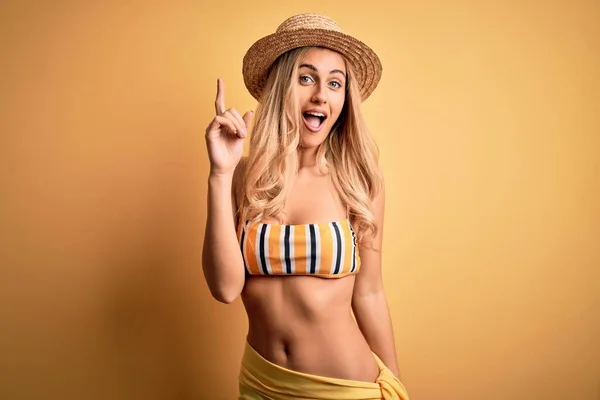 年轻美丽的金发女人在度假时穿着比基尼 头戴黄底帽 指指点点 想出了个好主意 又兴奋又快乐第一部分 — 图库照片