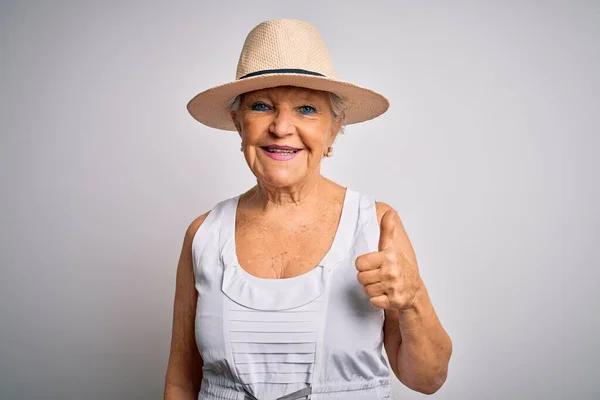 カジュアルな夏のドレスを着て休暇中のシニア美しい白髪の女性と手で幸せな親指アップジェスチャーを行う帽子 成功を示すカメラを見て表現を承認する — ストック写真
