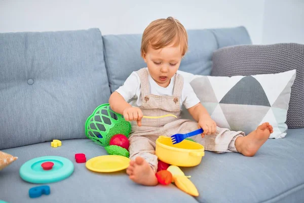 Sevimli Sarışın Çocuk Kanepede Oturup Evde Plastik Yemek Oyuncaklarıyla Oynuyor — Stok fotoğraf