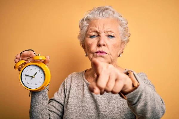 Senior Mooie Vrouw Met Wekker Staande Geïsoleerde Gele Achtergrond Wijzend — Stockfoto