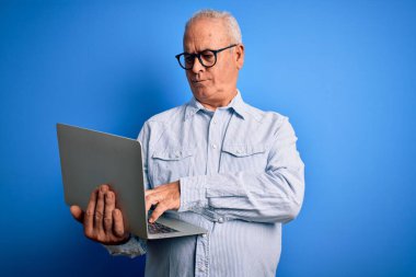 Orta yaşlı, yakışıklı, beyaz, gözlüklü bir iş adamı. Bilgisayarla çalışıyor. Yüzünde kendine güvenen bir ifade var.