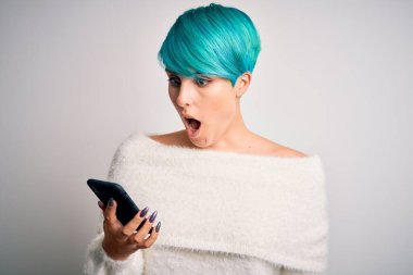 Mavi saçlı genç bir kadın akıllı telefon kullanarak konuşuyor. Şaşırmış bir yüzle korkmuş ve korku ifadesinden heyecanlanmış.