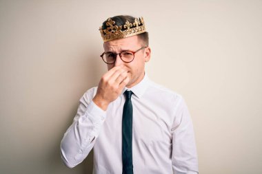 İzole edilmiş arka planda altın taç takan yakışıklı beyaz iş adamı pis ve iğrenç bir koku alıyor. Nefesini burnunda tutuyor. Kötü kokuyor.