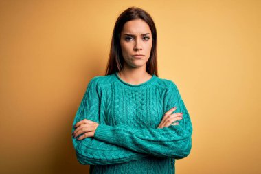 Sarı arka planda yeşil süveter giyen genç, güzel esmer kadın şüpheci ve gergin, yüzünde çapraz kollu tasvip etmeyen ifade. Negatif kişi.