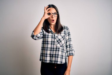 Mavi gözlü genç esmer kadın, beyaz arka planda günlük gömlek ve gözlük takıyor. Şaşırmış yüz ifadesiyle şaşırmış, parmaklarından bakan gözler. İnançsız ifade.