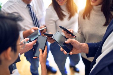 Ofiste el ele duran bir grup iş adamı akıllı telefonları kullanarak semboller yapıyor.