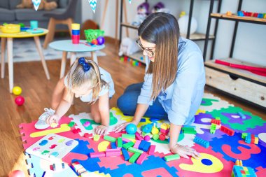 Beyaz kız çocuk, bayan öğretmenle oyun oynayıp öğreniyor. Anne ve kız oyun odasında oyuncaklarla oynuyorlar.