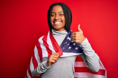 Bağımsızlık gününde Amerika Birleşik Devletleri bayrağı taşıyan, genç, Afro-Amerikan vatansever kadın gülümseyen, işaret veren, parmaklarıyla başparmağını kaldıran, mükemmel bir işaret.