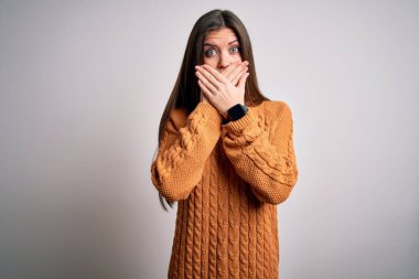Mavi gözlü genç bir kadın beyaz arka planda dikilen sıradan bir süveter giyiyor. Ağzını yanlışlıkla ellerle kapatıyor. Gizli konsept.