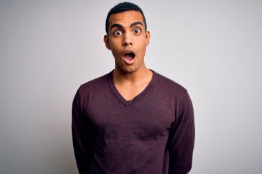 Beyaz arka plan üzerine gündelik süveter giyen genç ve yakışıklı Afro-Amerikan adam korku ve heyecan dolu bir yüz ifadesiyle korkmuş ve şok olmuştu..