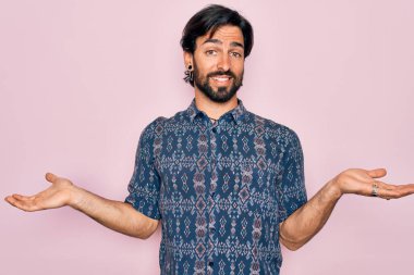 Pembe arka planda hippi tarzı giyinmiş genç, Latin asıllı bohem bir adam gülümseyerek avuçlarını açıyor, sunuyor ve reklam karşılaştırması yapıyor ve dengeyi sağlıyor.