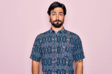 Genç, yakışıklı, bohem, pembe arka planda hippi tarzı giyinmiş, komik yüzlü yanakları şişiren bir adam. Havayla şişmiş ağız, çılgın bir ifade..