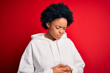 Kıvırcık saçlı, spor giyimli, midesi üstünde genç ve güzel Afro-Amerikan Afro kadın. Çünkü hazımsızlık, acı verici bir hastalık, kendini iyi hissetmiyor. Ache kavramı.