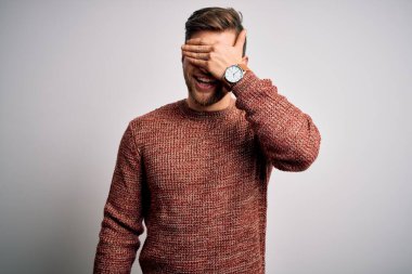 Sakallı, mavi gözlü, beyaz arka planda sıradan bir süveter giyen, gülümseyen ve gülen genç sarışın bir adam. Kör kavram.