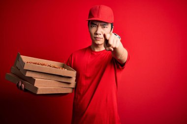 Genç yakışıklı Çinli teslimatçı elinde İtalyan pizzasıyla kutuları teslim ediyor. Kamerayı işaret ediyor ve sen, el işareti, ön taraftan pozitif ve kendinden emin bir jest.