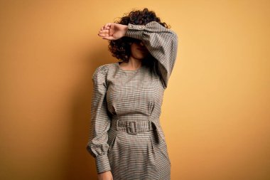 Güzel bir Arap iş kadını elbise ve gözlük takıyor sarı arka planda duruyor gözleri kollarıyla kaplıyor, ciddi ve üzgün görünüyor. Görme, saklama ve reddetme konsepti