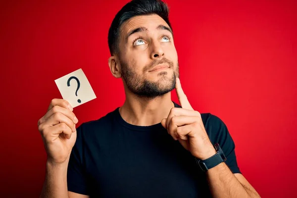 Junger Gutaussehender Mann Hält Papier Mit Fragezeichen Symbol Über Rotem — Stockfoto