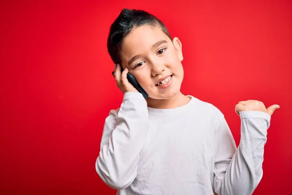 Маленький Мальчик Говорящий Мобильному Смартфону Красном Изолированном Фоне Указывая Пальцем — стоковое фото