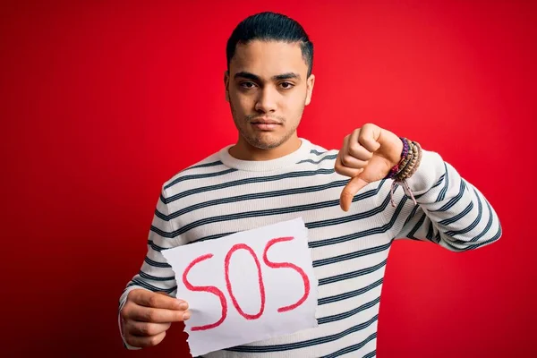 Kırmızı Arka Planda Afiş Tutmakta Zorlanan Genç Brezilyalı Adam Kızgın — Stok fotoğraf