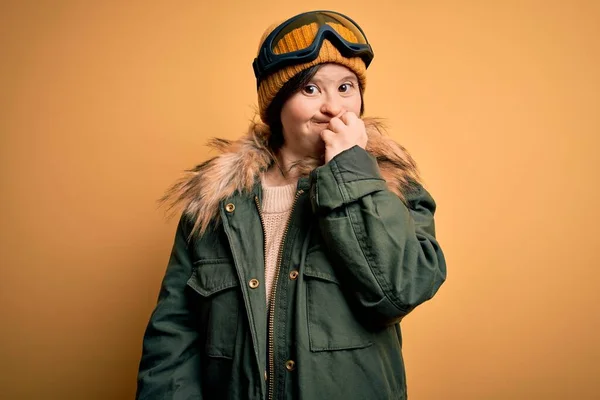 年轻的下意识的女人穿着滑雪外套 戴着眼镜过冬 看上去很紧张 双手放在咬指甲的嘴上 焦虑问题 — 图库照片