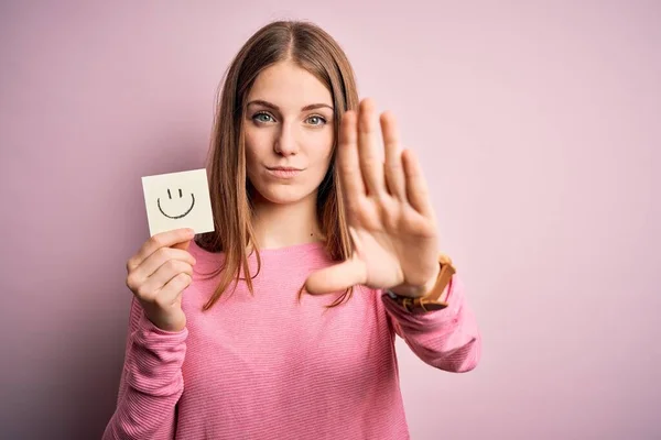 年轻美丽的红头发女人拿着写有微笑的提醒信 张开手做停止手势 严肃而自信的表情 防守手势 — 图库照片