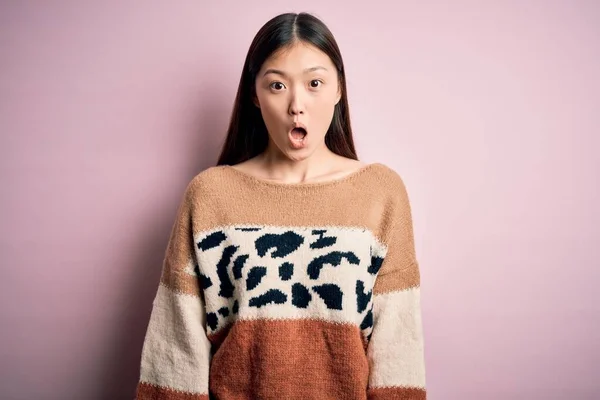 年轻美丽的亚洲女人穿着动物印花时装毛衣 披着粉色孤立的背景 害怕并震惊于惊讶的表情 恐惧和兴奋的脸 — 图库照片