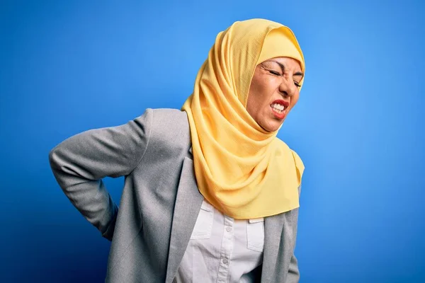 中年黑发女商人头戴穆斯林式的传统头巾 头戴蓝色背景的头巾 手背触痛 肌肉疼痛 — 图库照片