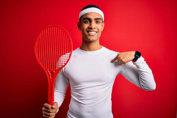 若いですハンサムなアフリカ系アメリカ人スポーツマン遊びテニス使用ラケット以上赤背景とともに驚き顔指して指へ彼自身 — ストック写真