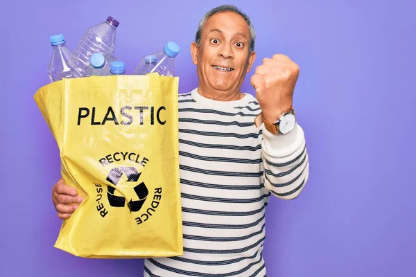 ビニールボトルで袋を保持リサイクルシニア男は誇りと勝利と成功を祝う叫び紫色の背景をリサイクルし 非常に興奮し 感情を応援 — ストック写真