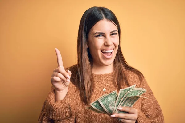 Joven Hermosa Mujer Sosteniendo Dólares Pie Sobre Fondo Naranja Aislado — Foto de Stock