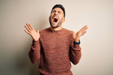 İzole edilmiş beyaz arka plan üzerinde dikilmiş kollarını kaldırmış ve gözlerini kapatmış heyecanlı bir şekilde başarı için deli ve çılgın bir kutlama yapan genç yakışıklı bir adam. Kazanan konsept