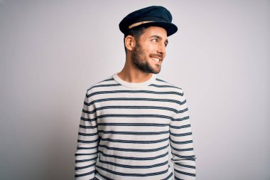 Sakallı, denizci üniformalı genç yakışıklı denizci ve Kaptan şapkası yüzünde gülümsemeyle, doğal bir ifadeyle yan yana bakıyor. Kendinden emin gülen.