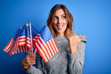 Amerika Birleşik Devletleri bayraklarını tutan genç ve güzel bir kadın beceriksizlik gününü kutluyor ve gülümseyen bir gülümsemeyle baş parmağıyla işaret ediyor.
