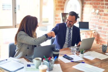 Mutlu ve kendinden emin gülümseyen iki orta yaşlı iş adamı. Yüzünde gülümsemeyle çalışmak ofiste yumruk tokuşturmak.