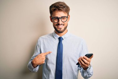 Genç iş adamı beyaz arka plan üzerinde akıllı telefon kullanarak kendini işaret ederek konuşuyor.