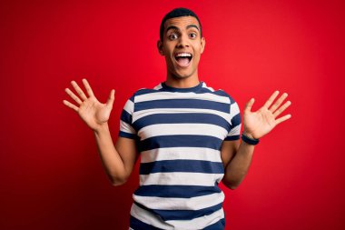 Yakışıklı Afro-Amerikalı adam kırmızı arka planda dikilmiş, sıradan çizgili tişört giyiyor. Çılgınlığı kutluyor ve başarıyı kollarını kaldırıp heyecanla çığlık atarak haykırıyor. Kazanan konsept