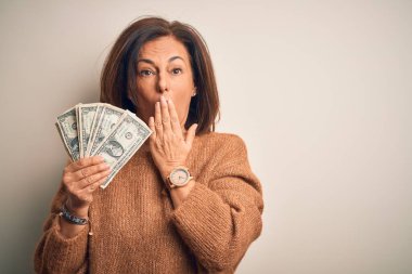 Orta yaşlı esmer kadın, elinde bir dolar banknotla izole edilmiş arka planda, ağzı kapalı, utancından ağzı açık, korkunun ifadesi, sessizlikten korkan, gizli bir konsept.