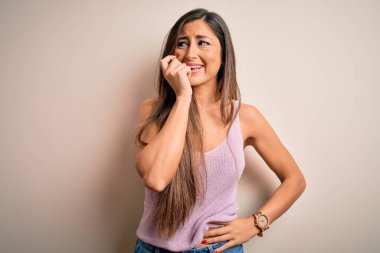 İzole edilmiş arka planda uzun saçlı, genç ve güzel esmer kadın elleri ağız ısıran tırnaklarla gergin ve stresli görünüyor. Endişe sorunu.