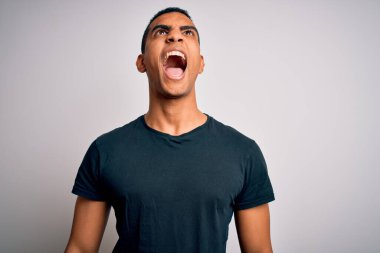 Genç, yakışıklı, Afro-Amerikalı bir adam, sıradan tişörtler giyip beyaz arka planda kızgın, öfkeli ve sinirli bir şekilde bağırıyor. Öfke ve agresif kavram.