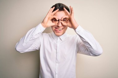 Genç yakışıklı iş adamları gözlük takıyor ve izole edilmiş arka planda zarif gömlekler giyiyor. Dürbünün dili dışarı çıkarması, gözlerin parmaklarından içeri bakması gibi güzel jestler yapıyor. Çılgın ifade.