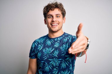 Sarışın, tatilde, kıvırcık saçlı, sıradan bir tişört giyen, dostça gülümseyerek selamlaşan genç, yakışıklı bir adam. Başarılı bir iş..