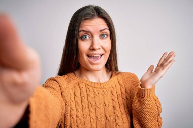 Mavi gözlü, sıradan süveter giyen genç bir kadın fotoğraf makinesiyle selfie yapıyor. Çok mutlu ve heyecanlı. Kazanan ifade zaferi büyük bir gülümsemeyle kutluyor ve ellerini kaldırıyor.