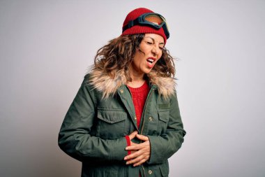 Orta yaşlı kayakçı kadın kar maskesi takıyor ve beyaz arka planda kayak gözlükleri takıyor midesi bulanıyor çünkü mide bulantısı ve acı veren bir hastalık var. Ache kavramı.