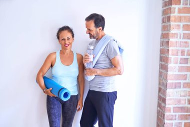 Orta yaşlı güzel sporcu çift mutlu gülümsüyor. Yüzünde gülümsemeyle spor salonunda kameraya bakarken.