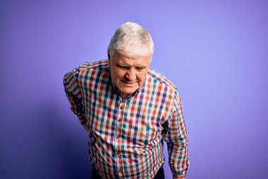 Kıdemli yakışıklı, beyaz gömlekli, soyutlanmış, mor arka planda, sırt ağrısı çeken, elleriyle dokunan, kaslı bir adam.